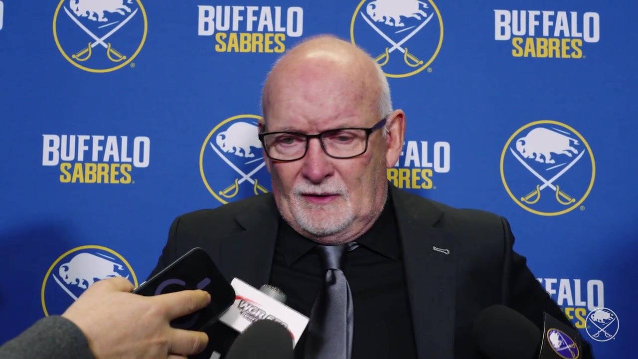 Lindy Ruff answers reporters’ questions in front of a Buffalo Sabres backdrop after the overtime loss in Montreal.
