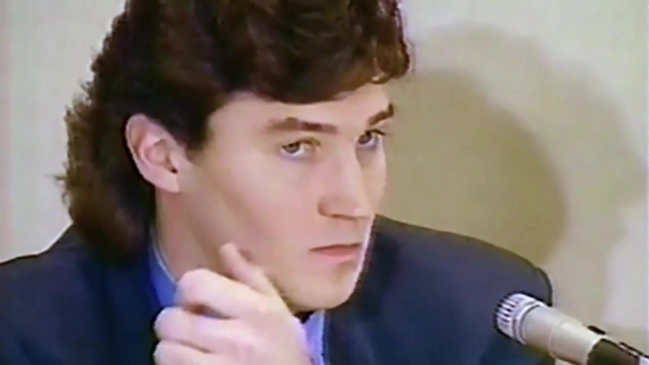Mario Lemieux sits beside a microphone during an archival press conference.