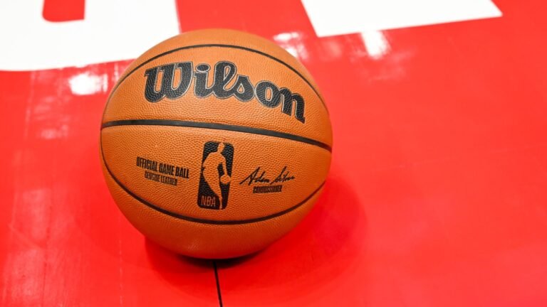 A Wilson NBA basketball resting on a red court surface.