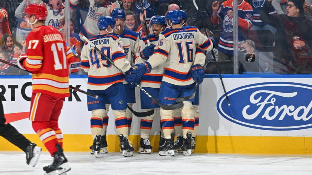 Edmonton players celebrate beside the boards with a Calgary player nearby at Rogers Place.
