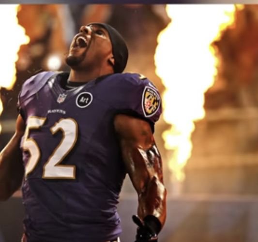 Ray Lewis in a purple Baltimore Ravens number 52 jersey beside stadium flames.