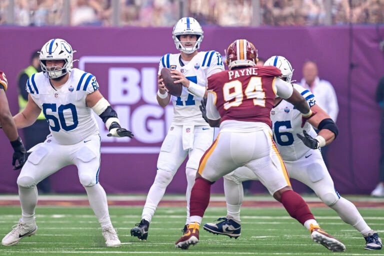 Daniel Jones holds the ball as Daron Payne approaches during Colts&ndash;Commanders in London