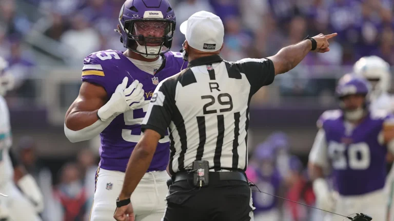 Referee Adrian Hill, wearing No. 29, points while Vikings linebacker Eric Wilson stands beside him.