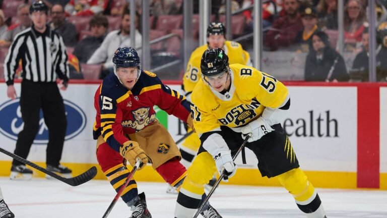 Matt Poitras in a yellow Boston Bruins jersey skating beside a Florida Panthers player.