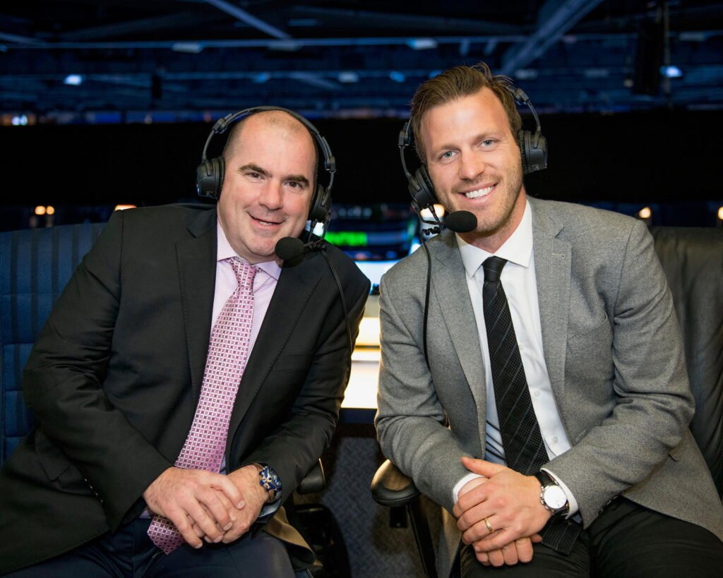 Blues broadcasters Chris Kerber and Joey Vitale wearing headsets in the broadcast booth