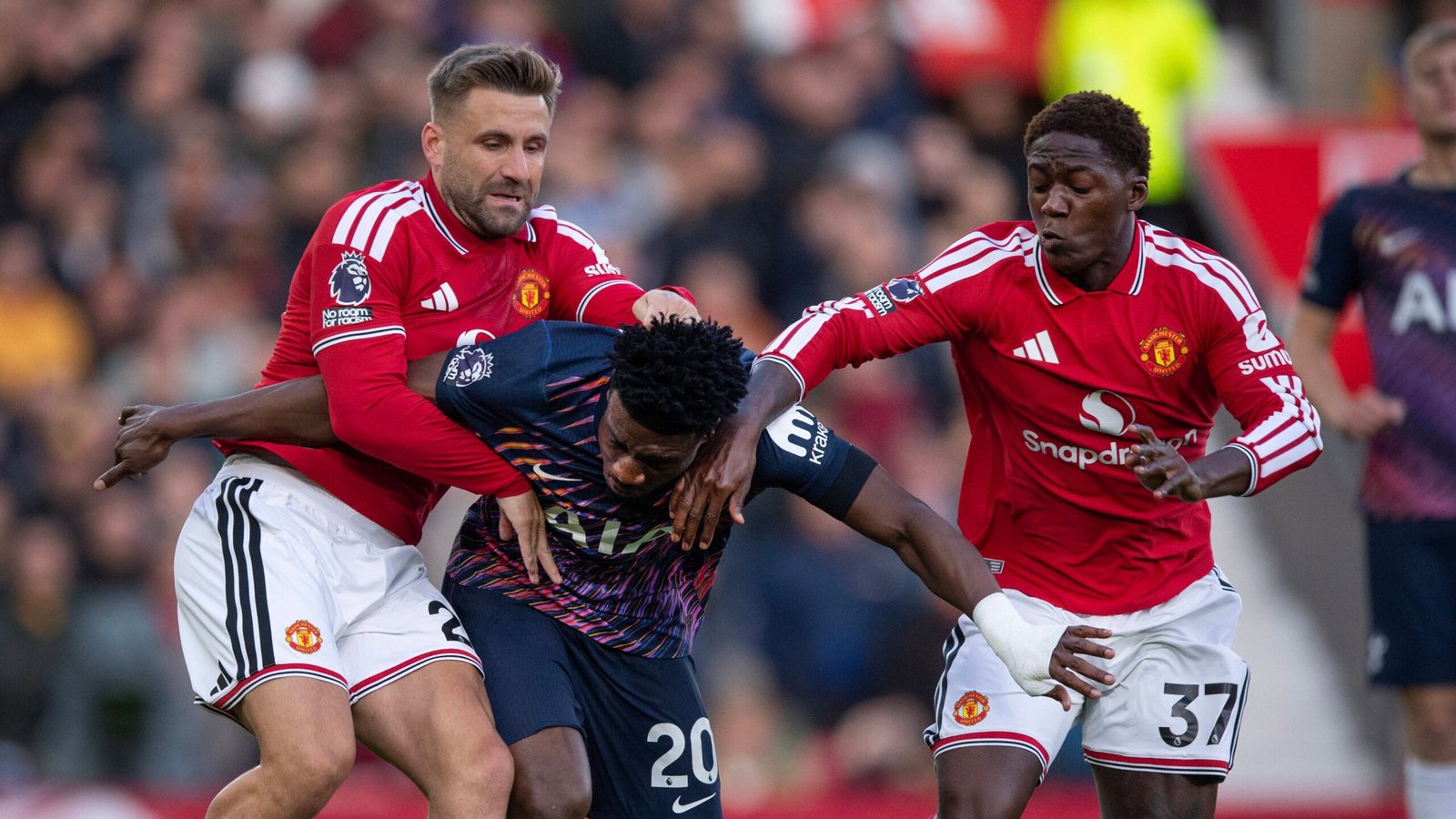 Luke Shaw and Kobbie Mainoo challenging an opponent while playing for Manchester United