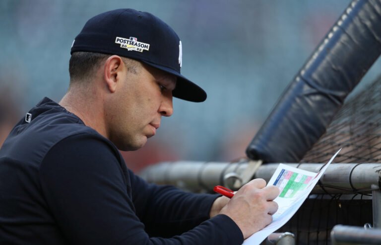 Dillon Lawson taking notes beside a batting cage in a Yankees uniform