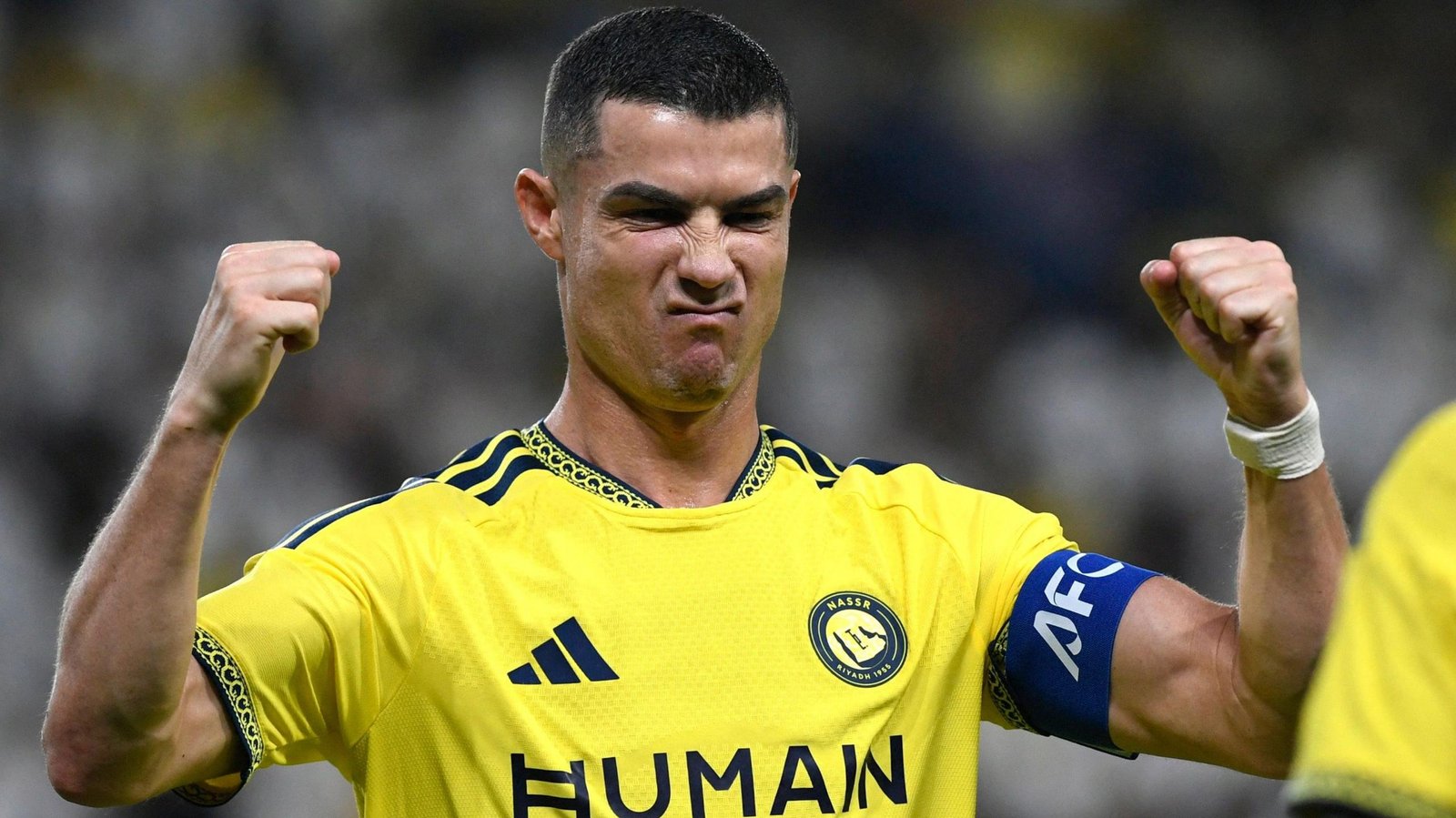 Cristiano Ronaldo celebrating in Al-Nassr's yellow shirt with both fists raised