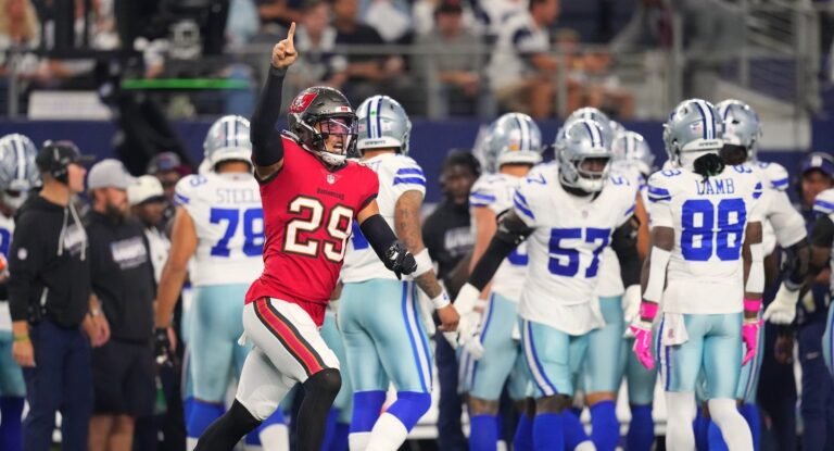 Buccaneers player Miles Killebrew raising his arm with Dallas Cowboys players behind him