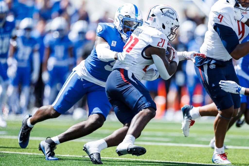 A Kentucky defender wraps up a South Alabama ball carrier on the field.