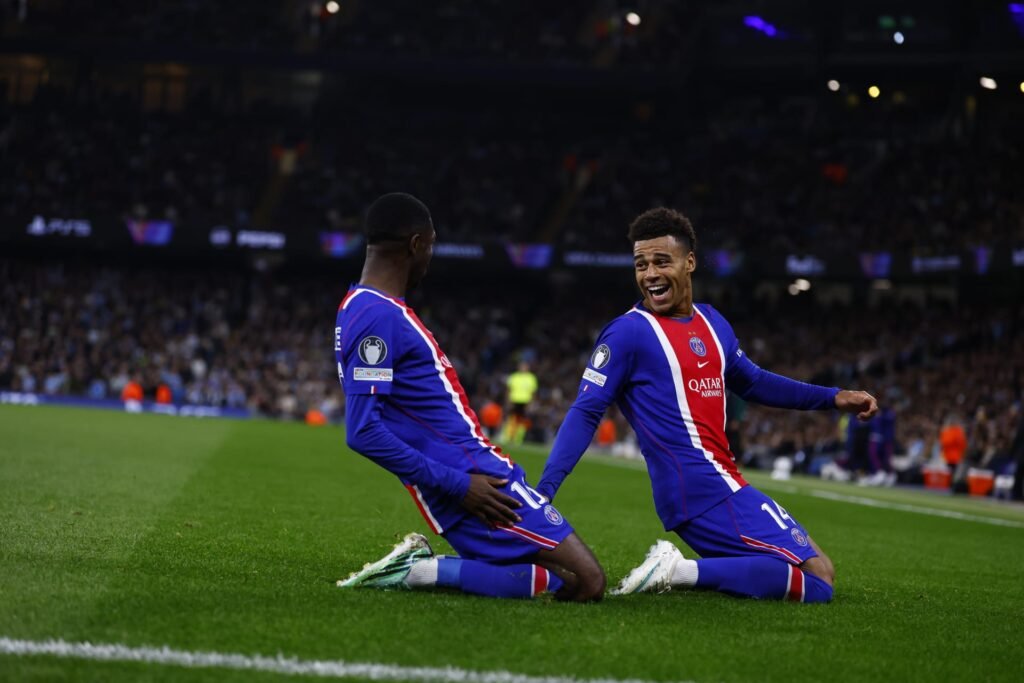 PSG players celebrate together on their knees near the sideline during a Champions League match.