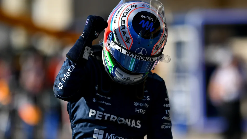Kimi Antonelli raises a fist while wearing his Mercedes helmet.