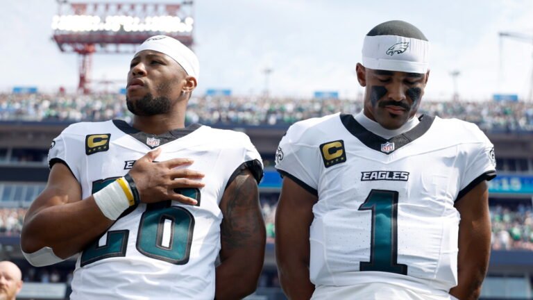 Saquon Barkley and Jalen Hurts standing together in Eagles uniforms before a game