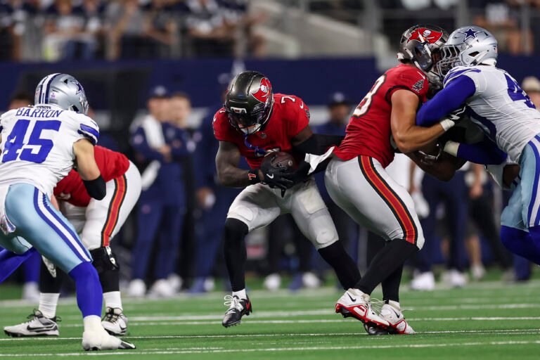 Bucky Irving, wearing No. 7, carries the ball behind Tampa Bay blockers against Dallas.