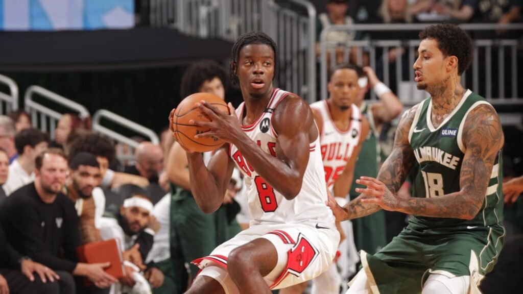 A Chicago Bulls player holds the basketball beside a Milwaukee Bucks defender.