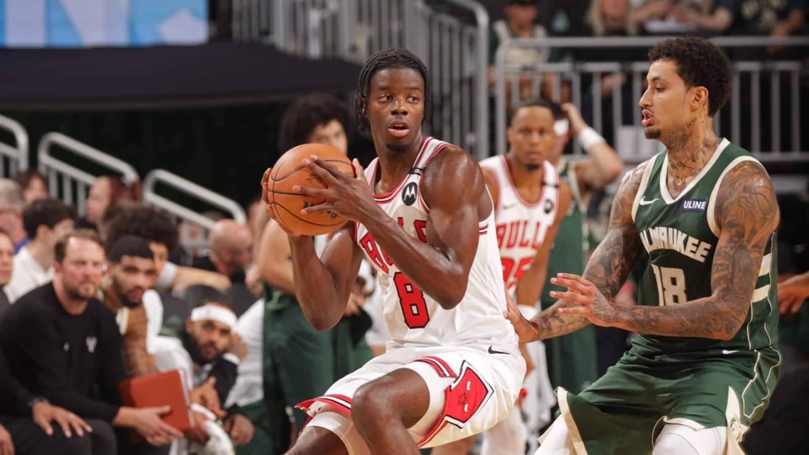 A Chicago Bulls player holds the basketball beside a Milwaukee Bucks defender.