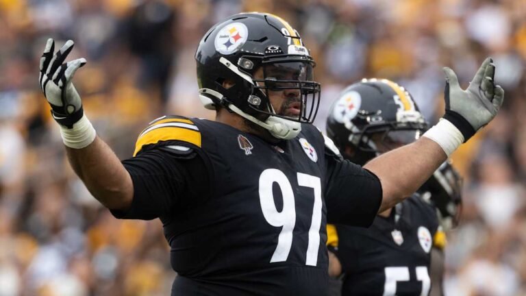 Cam Heyward in a black Pittsburgh Steelers uniform with his arms raised.