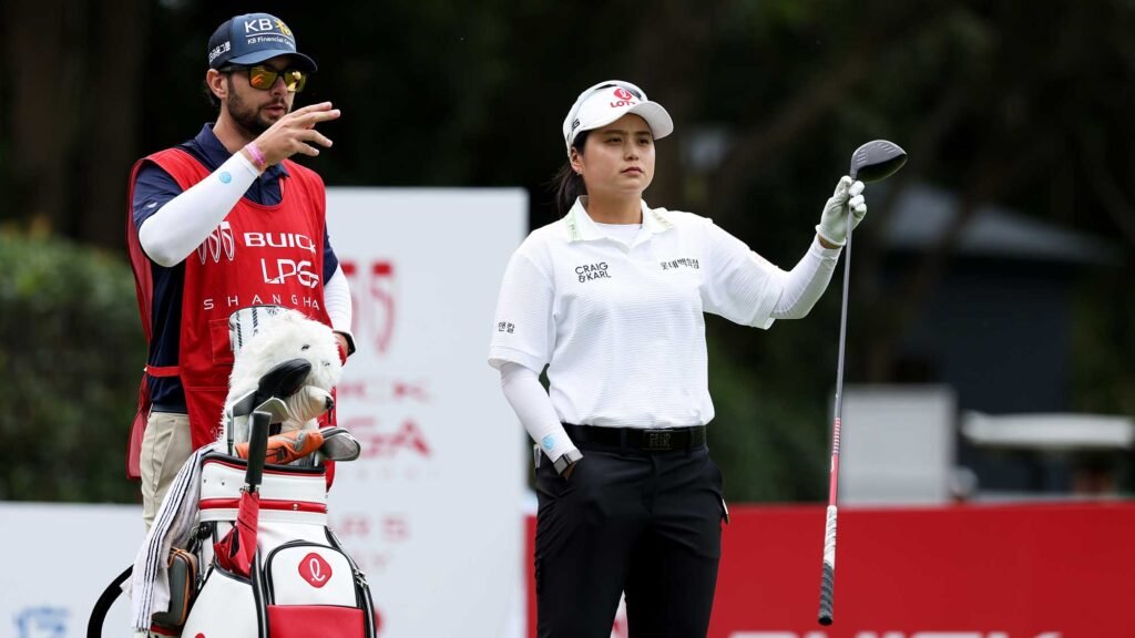 Hye-Jin Choi holds a club beside her caddie at the eighth tee during the first round in Shanghai.