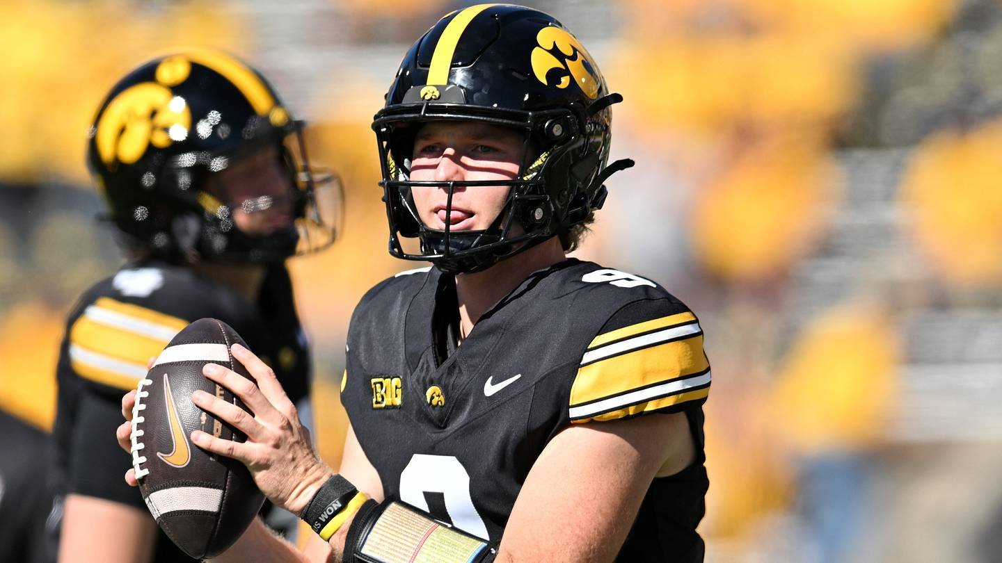 Hank Brown holding a football while warming up in an Iowa number 9 jersey.