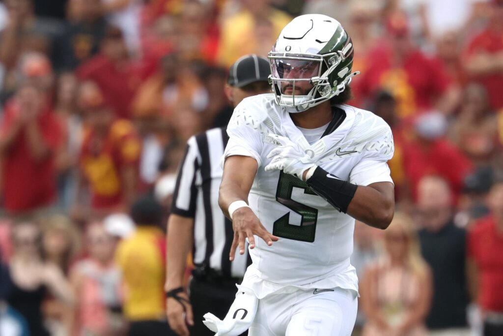 Dante Moore in a white Oregon number 5 uniform following through on a throw.