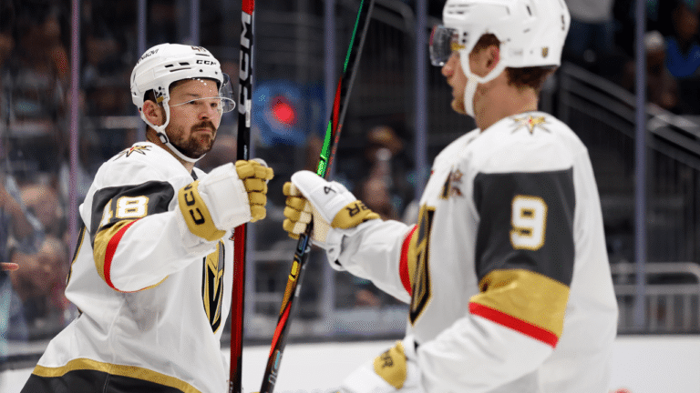 Tomas Hertl and Jack Eichel touch gloves in white Vegas Golden Knights uniforms.
