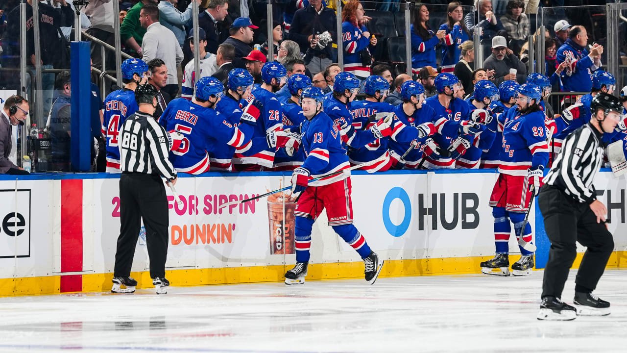 Alexis Lafrenière celebrates by the New York Rangers bench, with Mika Zibanejad nearby.