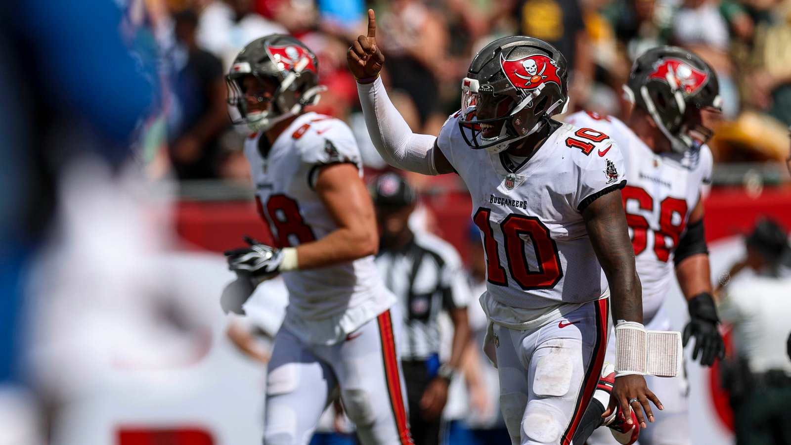 Jalon Daniels in a white Tampa Bay jersey and helmet raises one finger on the sideline.