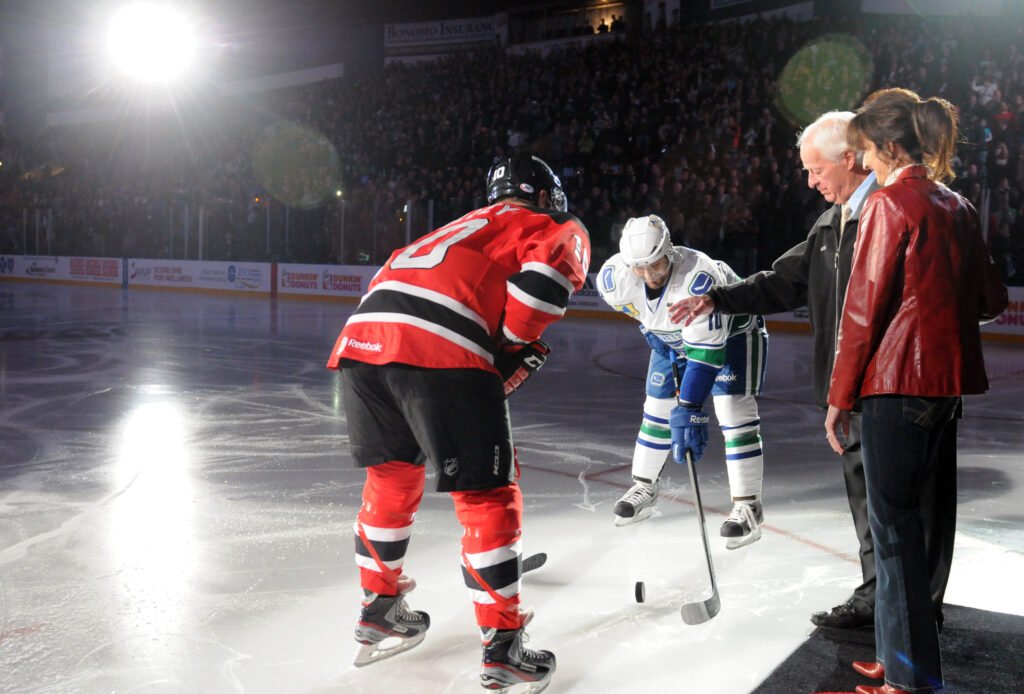 Gordie Howe drops a ceremonial puck between two players at the Utica Comets' 2013 home opener.