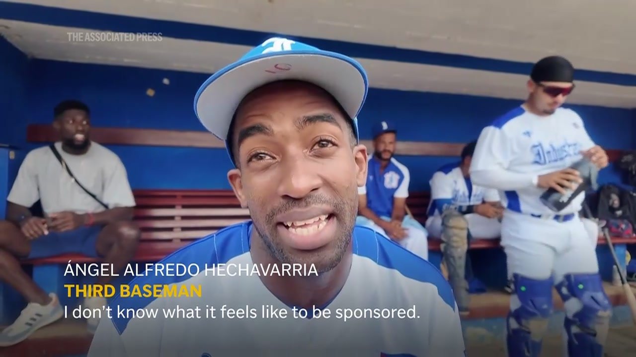 Industriales third baseman Ángel Alfredo Hechavarria speaks to AP in the Havana dugout about the team’s new jersey sponsor.