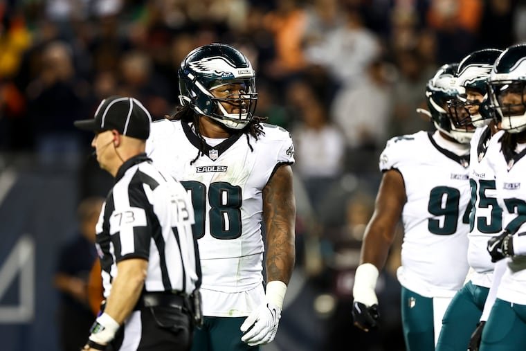 Jalen Carter stands beside Eagles teammates in his white No. 98 uniform.