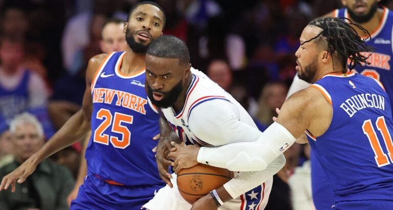 Jaylen Brown holding the ball in a white 76ers jersey as Jalen Brunson defends.