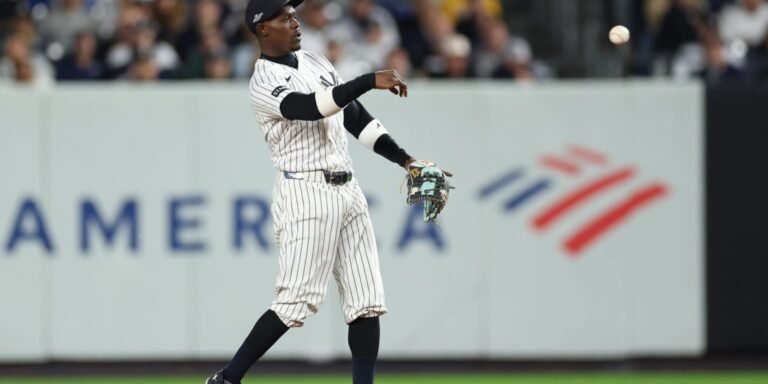 Jazz Chisholm Jr. throwing a baseball in a Yankees pinstriped uniform.