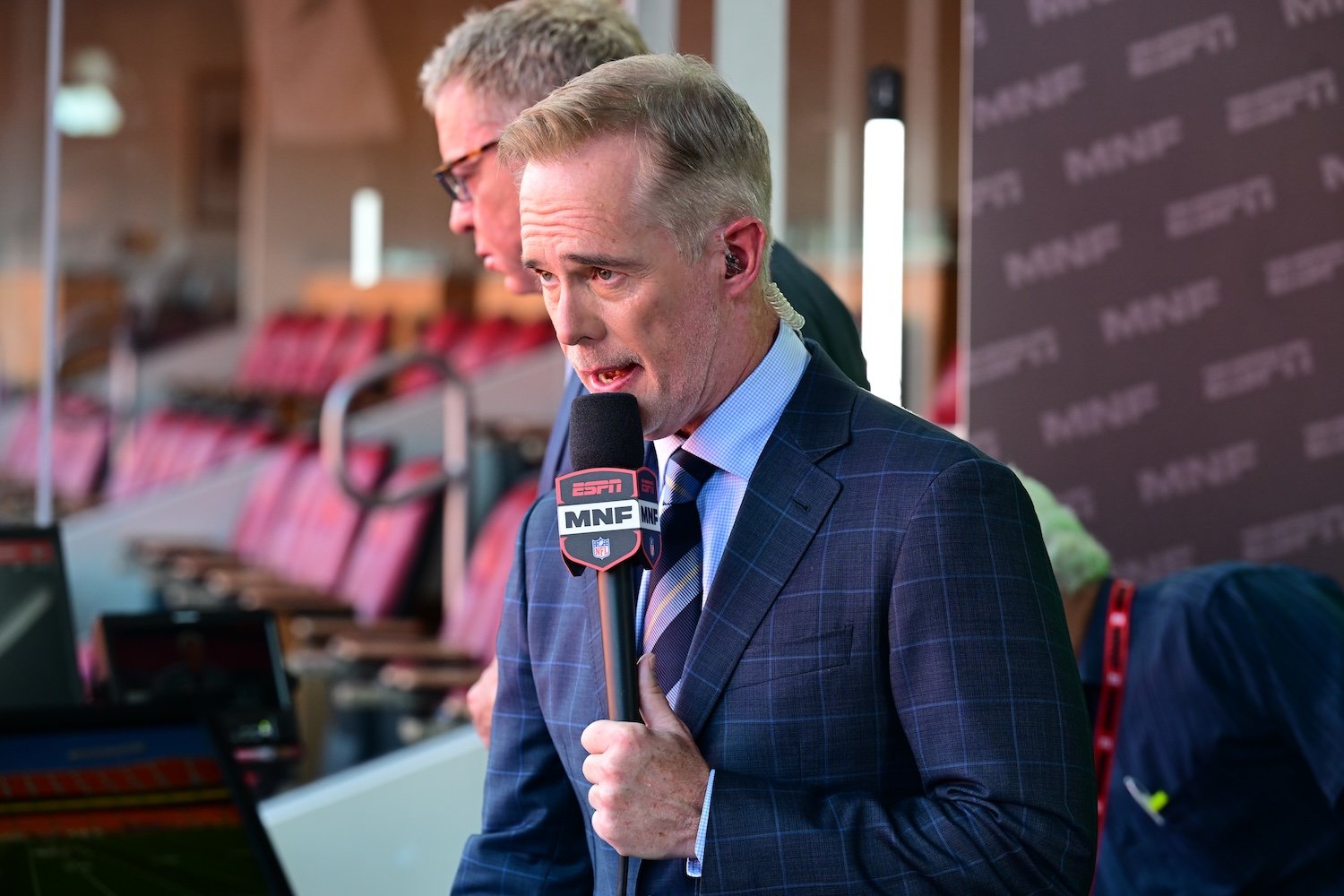Joe Buck holding an ESPN microphone in the Monday Night Football booth at Arrowhead Stadium on September 14, 2026.