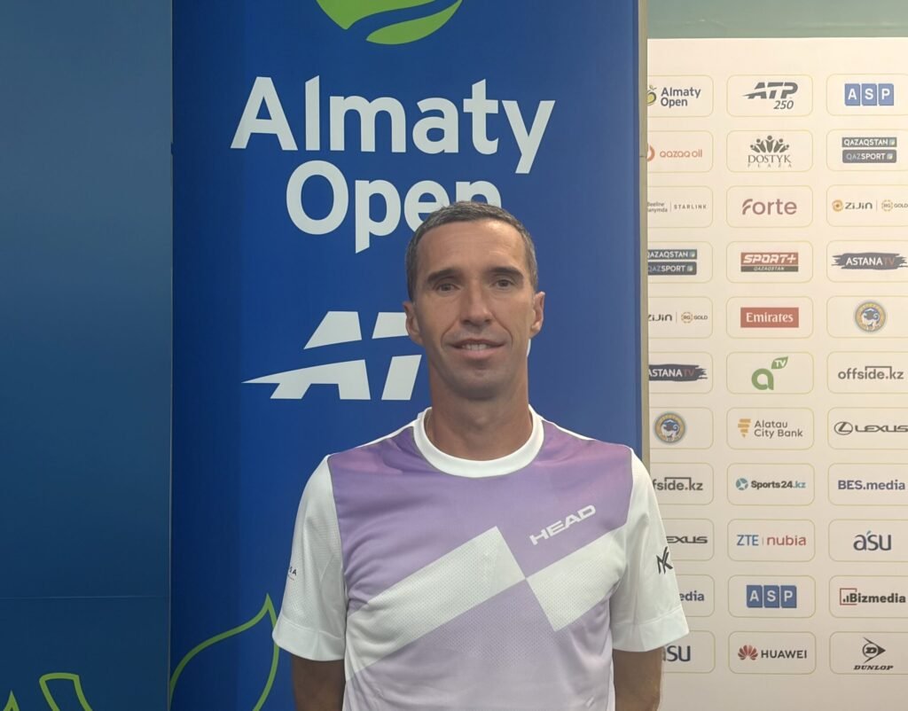 Kukushkin stands in front of the Almaty Open interview backdrop.
