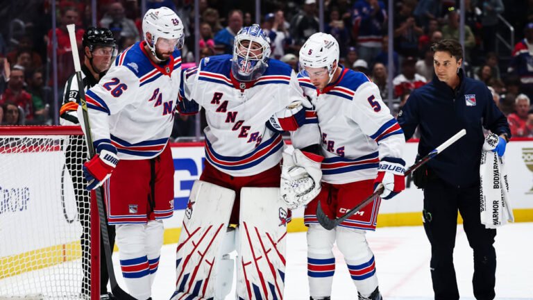 Igor Shesterkin is helped off the ice by Rangers teammates.