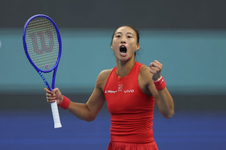 Zheng Qinwen celebrates with her racket and fist raised.