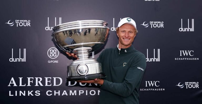 Adrian Meronk holds the Dunhill Links trophy in front of the tournament backdrop.