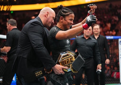 Natalia Silva raises her arms as the UFC championship belt is fastened around her waist.