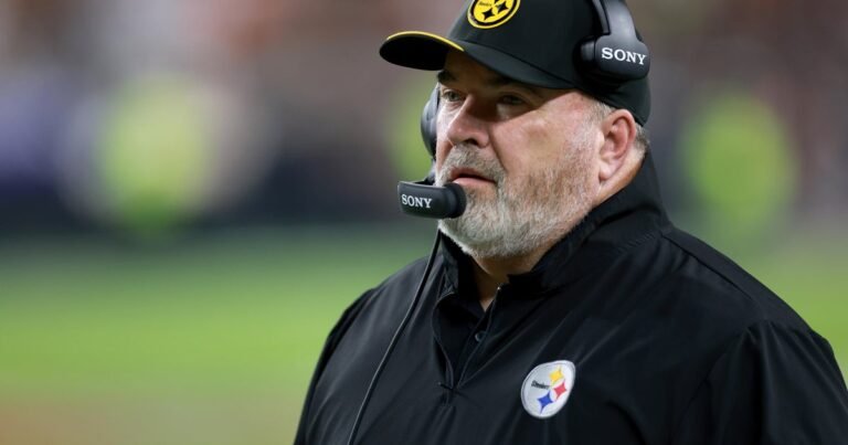Mike McCarthy wears a Steelers cap and headset on the sideline.