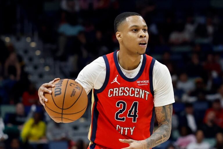 Jordan Hawkins holding the ball in a red New Orleans Pelicans jersey.