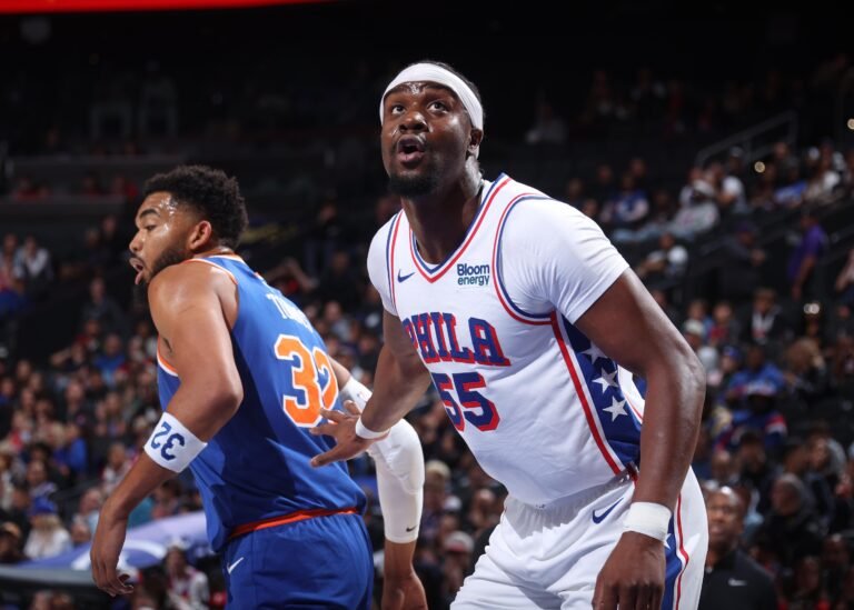 Ariel Hukporti in a white 76ers jersey boxing out Karl-Anthony Towns.
