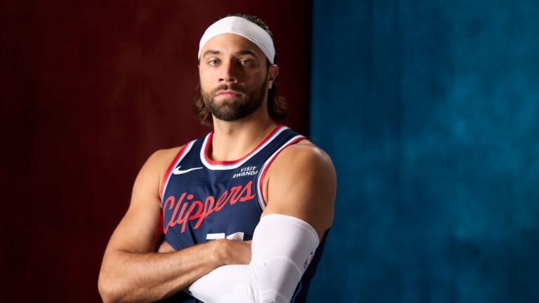 Max Strus posing with his arms crossed in a blue Clippers jersey.
