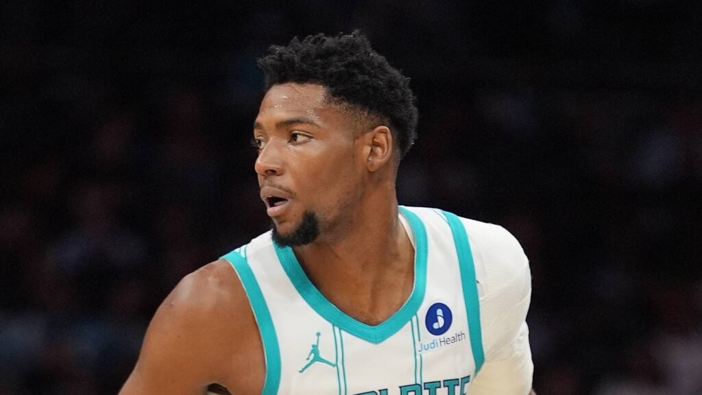 Brandon Miller in a white Charlotte Hornets jersey looking across the court.