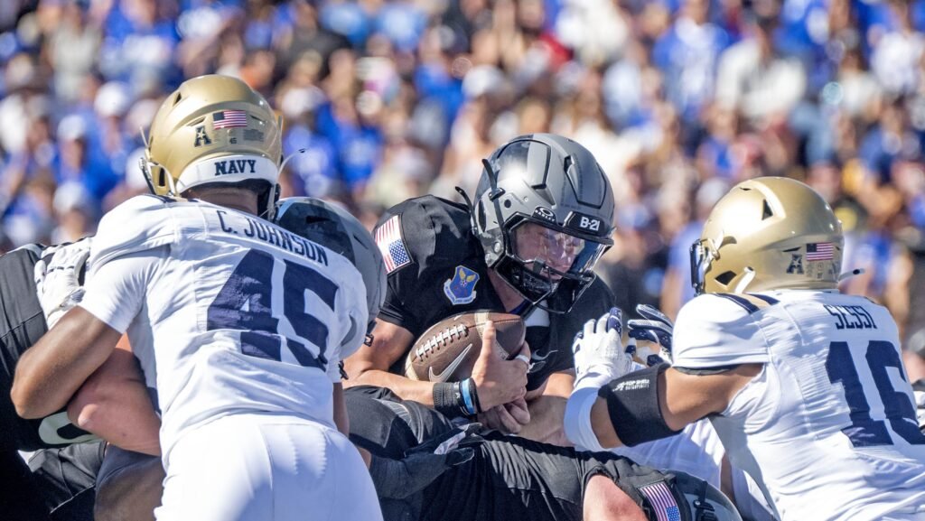 Air Force quarterback Liam Szarka carrying the football between Navy defenders at Falcon Stadium.