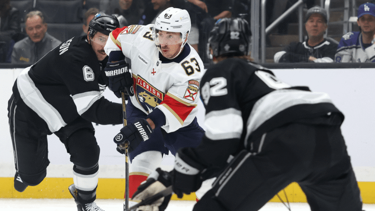 Brad Marchand in a white Florida Panthers jersey skating between Los Angeles Kings players.