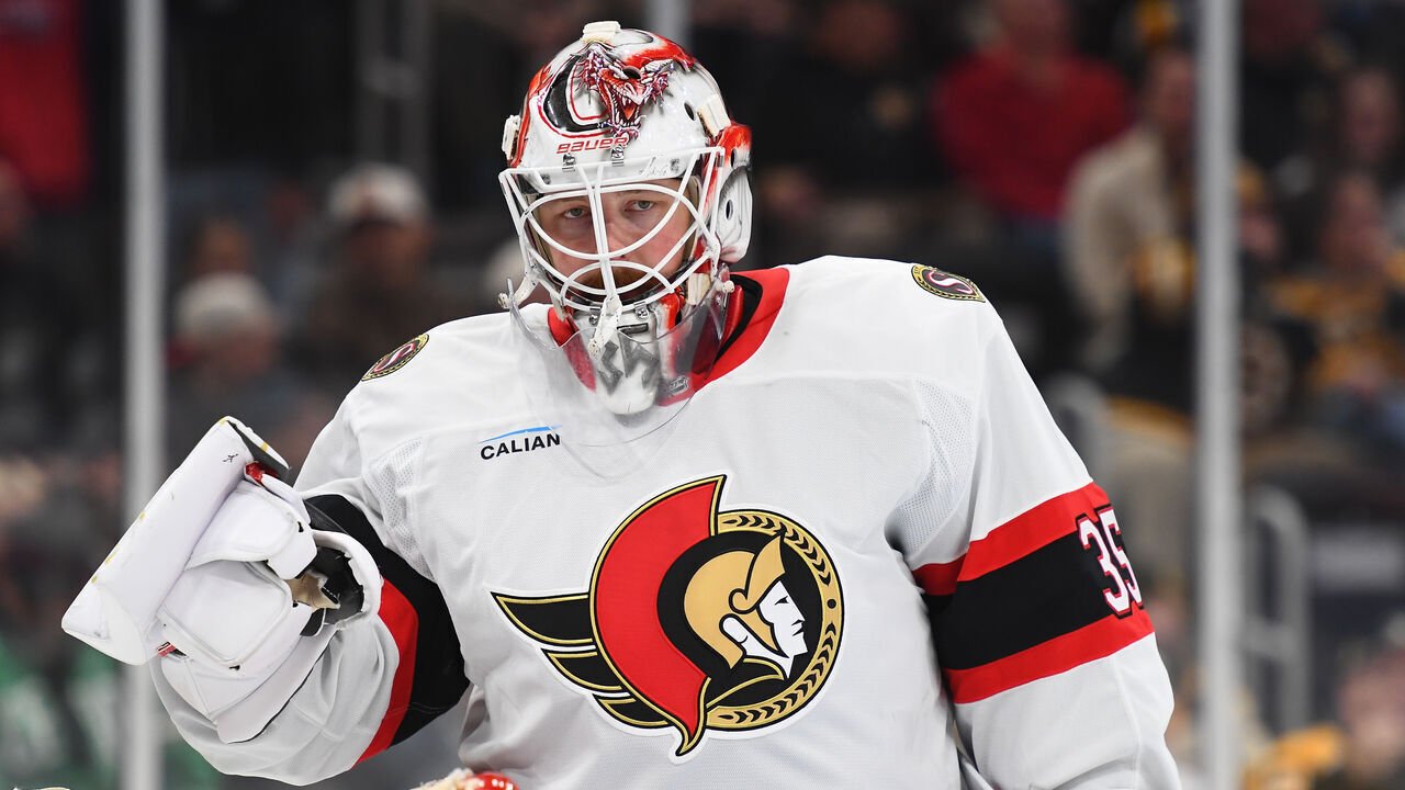 Linus Ullmark wearing a white Ottawa Senators jersey and a white and red goalie mask.