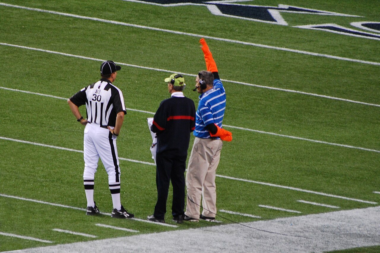 An NFL official confers with two sideline television coordinators in Seattle