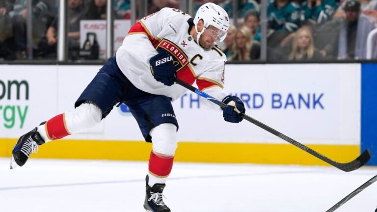Aleksander Barkov playing the puck in a white Florida Panthers jersey.