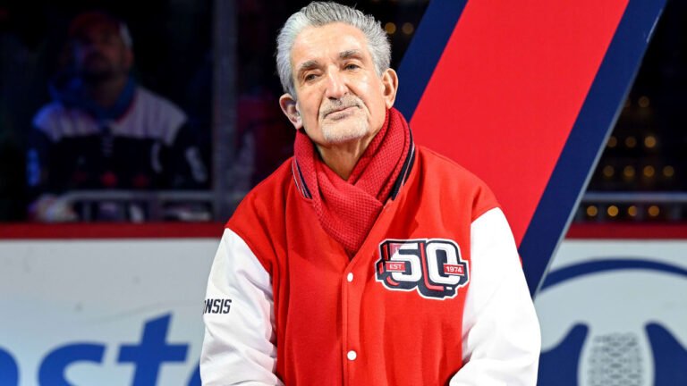 Ted Leonsis wearing a red Capitals jacket and scarf at an ice rink.