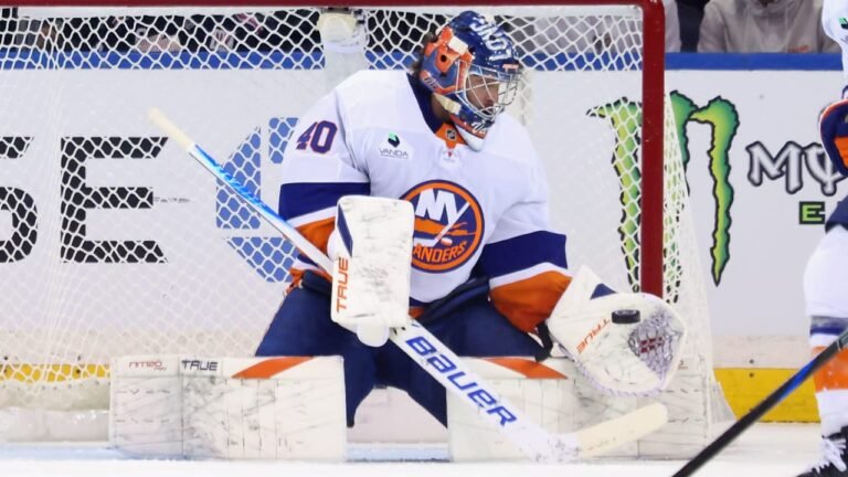Semyon Varlamov in a white Islanders jersey guarding the net.